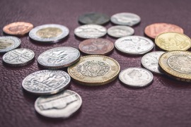 Mynt liggande på ett underlag av lila skinn.